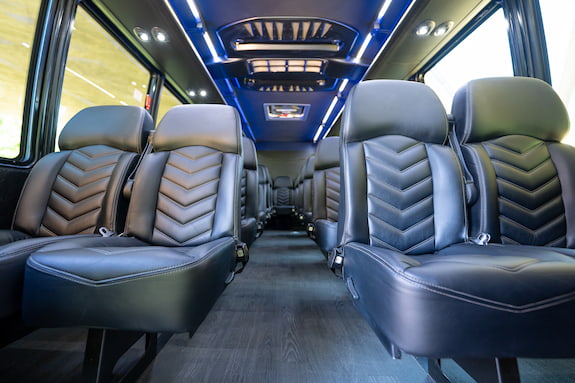 a row of leather seats and blue ceiling lights on a minibus