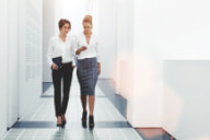 two employees walk together and look at a phone